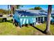 Rear exterior view of the house with a teal facade, AC unit, and green lawn at 2465 Northside Dr # 1808, Clearwater, FL 33761