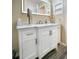 Bright bathroom vanity with marble countertop, white cabinets, and a large, illuminated mirror at 6321 Staunton Dr, Holiday, FL 34690