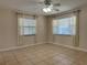 Neutral bedroom with tile flooring, ceiling fan, two bright windows with white curtains and blinds at 8153 22Nd N Ave, St Petersburg, FL 33710