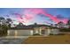 Single-story home at sunset with white exterior and double garage at 16117 Medrick Rd, Brooksville, FL 34614