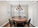 Bright dining room features a round wooden table with four chairs and a beautiful chandelier at 21361 Snowy Orchid Ter, Land O Lakes, FL 34637