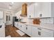 Modern kitchen with white cabinets, quartz countertops, and a wood range hood at 21361 Snowy Orchid Ter, Land O Lakes, FL 34637