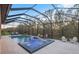A screened pool and spa are accompanied by a waterfall feature and outdoor lounge area with fire pit at 13019 Paddock Wood Pl, Riverview, FL 33579