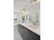 Bathroom featuring double sinks, a large mirror, a soaking tub, a glass shower, and stylish dark gray cabinets at 1530 W River Shore Way, Tampa, FL 33603