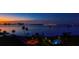 Night view featuring palm trees, a pool and buildings against a colorful and vibrant sky and waterfront at 3 Seaside Ln # 601, Belleair, FL 33756
