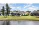 Backyard view featuring the serene lake and the home's well-manicured surroundings at 5556 Sabal Trace Dr, North Port, FL 34287