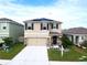 Inviting two-story home featuring a well-manicured lawn, complemented by a two-car garage and solar panels at 5808 Calla Lilly Dr, Sarasota, FL 34232