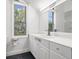 Bright bathroom with white vanity, large mirror, and window offering a view at 1328 Pelican Creek Xing # D, St Petersburg, FL 33707