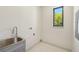 Convenient laundry room with a stainless steel sink, patterned floors, and a view of a mature tree outside at 1412 S Moody Ave # A, Tampa, FL 33629