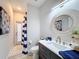 Modern bathroom with dark vanity, round mirror, and blue and white accents at 2811 Windcrest Oaks Ct, Valrico, FL 33594