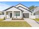 Modern two-story home with white siding, dark trim, a covered porch, and a driveway leading to an attached garage at 3006 E Columbus Dr, Tampa, FL 33605