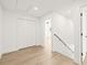 Hallway with white walls, louvered closet doors, light wood floors, and a staircase at 3006 E Columbus Dr, Tampa, FL 33605
