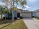 One-story home with blue exterior, two-car garage, and landscaped lawn at 10119 Rose Petal Pl, Riverview, FL 33578