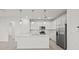 Stunning white kitchen featuring a center island, stainless steel appliances, modern pendant lighting, and ample counter space at 3065 Winding Creek Trl, North Port, FL 34289