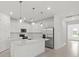 Bright, spacious kitchen with white cabinetry, stainless steel appliances, a center island, and modern pendant lighting at 3065 Winding Creek Trl, North Port, FL 34289