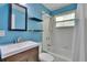 Bright blue bathroom with a tub, shower, modern fixtures, and floating shelves at 6524 14Th N St, St Petersburg, FL 33702