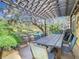 Outdoor dining area under a pergola with a built-in fire pit and views of the greenery at 16829 Midsummer Ln, Spring Hill, FL 34610