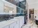 Elegant bathroom with dual vanities, marble tile, a walk-in shower, and a closet at 16829 Midsummer Ln, Spring Hill, FL 34610