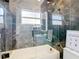 Modern bathroom with marble tile, white tub, glass shower, and black fixtures at 16829 Midsummer Ln, Spring Hill, FL 34610