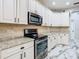Modern kitchen boasts white cabinets, stainless steel appliances, and sleek granite countertops at 16829 Midsummer Ln, Spring Hill, FL 34610