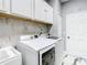 Laundry room featuring white cabinets, washer, dryer, and sleek marble tile flooring at 16829 Midsummer Ln, Spring Hill, FL 34610