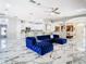 Spacious open living area with blue velvet sectional, marble floors, and view of kitchen at 16829 Midsummer Ln, Spring Hill, FL 34610