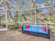 Relaxing screened patio area with a blue sofa, colorful pillows, and lush greenery at 16829 Midsummer Ln, Spring Hill, FL 34610