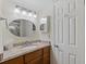 Well-lit bathroom with oval mirror, granite countertop, and wooden vanity at 6321 Newtown Cir # 21B4, Tampa, FL 33615