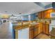 Open kitchen with granite countertops, wood cabinets, and view of the living area at 637 Pinellas Bayway S # 111, St Petersburg, FL 33715