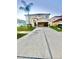 Two-story home showcasing a spacious driveway and an attached two-car garage, complemented by a manicured lawn and palm tree at 7423 Pulteney Dr, Zephyrhills, FL 33545