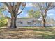 House exterior showcasing a Ranch style home with a gray painted exterior, landscaping, and large trees at 1316 S Evergreen Ave, Clearwater, FL 33756