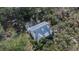 Aerial view of a home with solar panels, screened pool, lush trees, and a private lot at 1406 Butch Cassidy Trl, Wimauma, FL 33598