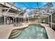 A refreshing screened-in pool area featuring a large in-ground pool, lounge chairs, and manicured landscaping at 1406 Butch Cassidy Trl, Wimauma, FL 33598