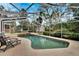 A refreshing screened-in pool area featuring a large in-ground pool, lounge chairs, and lush landscaping at 1406 Butch Cassidy Trl, Wimauma, FL 33598