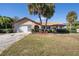 Single-story home with attached garage, mature landscaping, and palm trees at 15933 Adobe Dr, Hudson, FL 34667