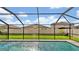 Relaxing screened pool area with a grassy backyard and surrounding homes at 16615 Parker River St, Wimauma, FL 33598