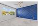 Spacious bedroom with blue accent wall, plush carpet, and large window at 6421 Mooring Line Cir, Apollo Beach, FL 33572