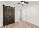 Bedroom featuring wood-look flooring, ceiling fan, and sliding barn door at 9890 54Th N St, Pinellas Park, FL 33782