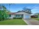 Front view of a single-story home with a green door, attached garage, and landscaped yard at 720 Lake Palms Dr, Largo, FL 33771