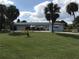 Light blue, single-story home with a two-car garage, surrounded by palm trees and a green lawn at 644 Blue Nw Ln, Port Charlotte, FL 33952