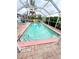Enclosed pool area with a pink-bordered pool and tropical landscaping at 644 Blue Nw Ln, Port Charlotte, FL 33952