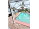 Screened-in pool with a pink border, surrounded by tropical landscaping at 644 Blue Nw Ln, Port Charlotte, FL 33952
