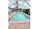 In-ground pool with a screened enclosure, surrounded by palm trees and greenery at 644 Blue Nw Ln, Port Charlotte, FL 33952