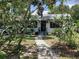 Charming home with a well-manicured lawn and inviting walkway through lush trees and flowers at 1529 Paloma Ln, Dunedin, FL 34698