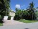 Front yard features a paved driveway, white garage door, and tropical foliage at 24 160Th Ct, Redington Beach, FL 33708