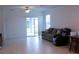 Living room with sliding glass doors, light tile flooring, and a comfortable sofa at 16851 Forge Surf St, Land O Lakes, FL 34638