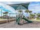 Community playground with a green slide, climbing features, and shade at 20375 Symphony Pl, Venice, FL 34293