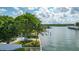 Waterfront home with lush trees, a white fence, and a private dock at 341 Bahia Vista Dr, Indian Rocks Beach, FL 33785