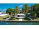 Charming waterfront home with lush tropical landscaping, white picket fence, and bright blue patio chairs at 341 Bahia Vista Dr, Indian Rocks Beach, FL 33785