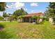 Lawn view of a home featuring a screened lanai and a terracotta tile roof, surrounded by mature landscaping and palm trees at 4327 Murfield E Dr, Bradenton, FL 34203